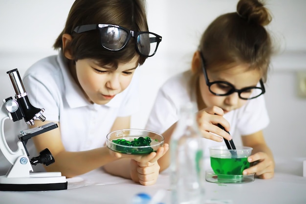 Duas crianças fofas na aula de química fazendo experimentos isolados no fundo branco