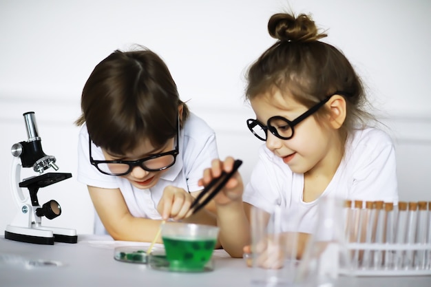 Duas crianças fofas na aula de química fazendo experimentos isolados no fundo branco