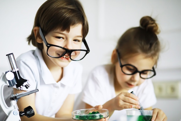 Duas crianças fofas na aula de química fazendo experimentos isolados no fundo branco