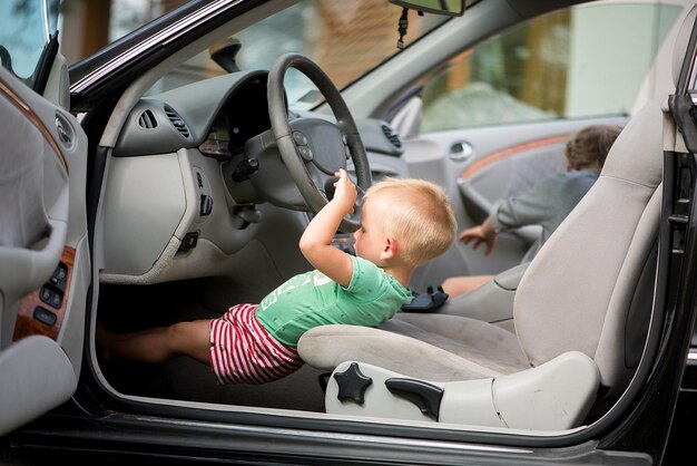 Duas crianças fofas, um irmão e uma irmã brincando de dirigir o carro ao volante
