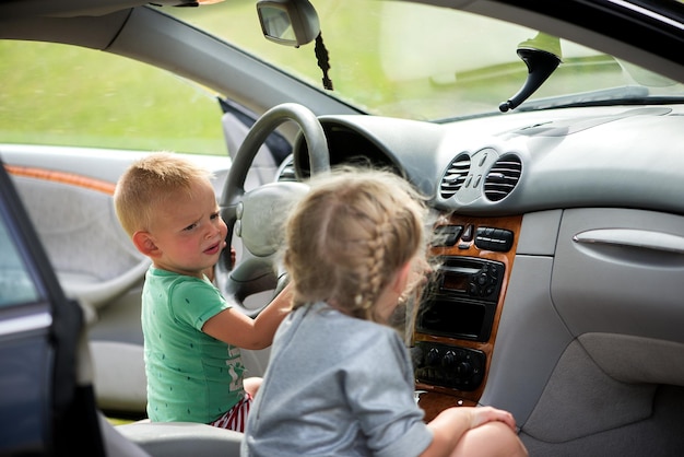 Duas crianças fofas, um irmão e uma irmã brincando de dirigir o carro ao volante