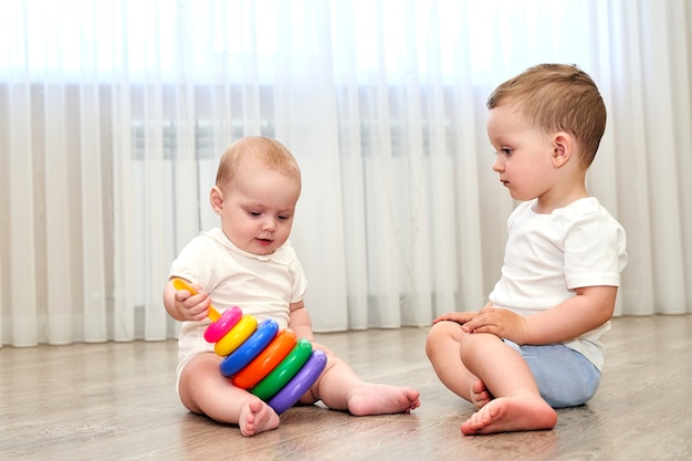 Foto duas crianças pequenas com olhos azuis brincando na sala de jogos.