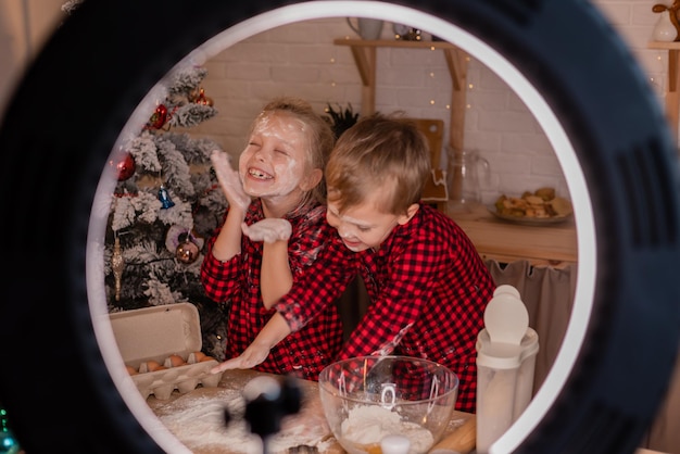 Duas crianças pequenas cozinham uma torta para o natal e gravam um blog de culinária. blogueiros infantis