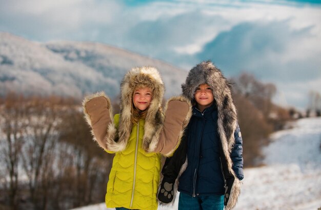 Duas crianças pequenas se divertem na bela natureza de inverno com neve coberta montanha rural