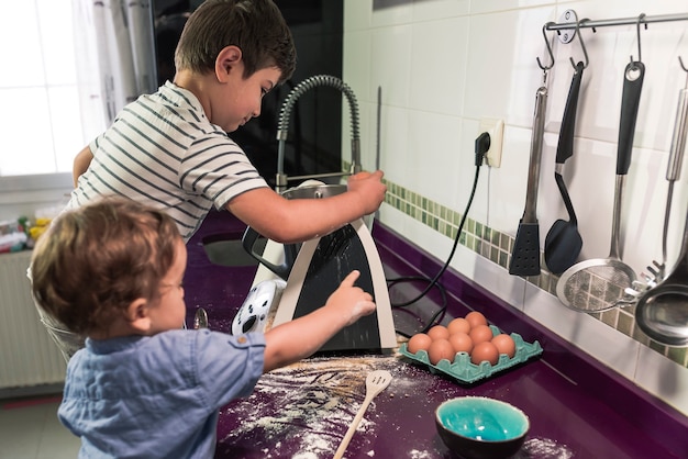 Duas crianças preparando panquecas com um robô de cozinha.