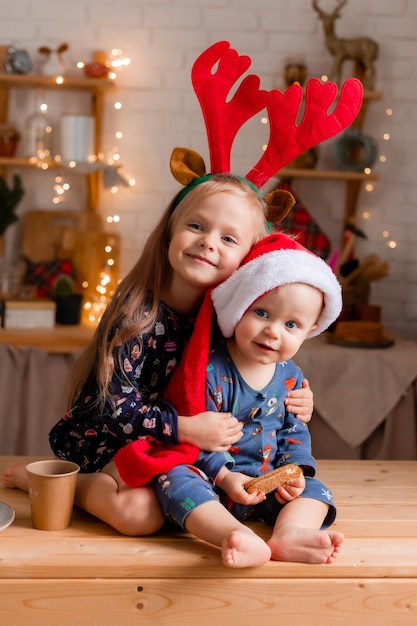 Duas crianças, um menino e uma menina, comem biscoitos na cozinha no dia de Natal. Foto de alta qualidade.