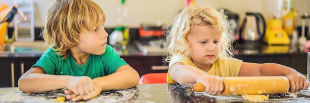 Duas crianças, um menino e uma menina, fazem biscoitos de formato longo de banner de massa