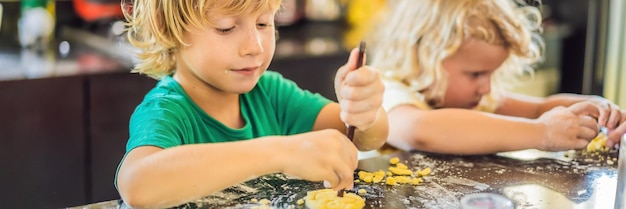 Duas crianças, um menino e uma menina, fazem biscoitos de formato longo de banner de massa