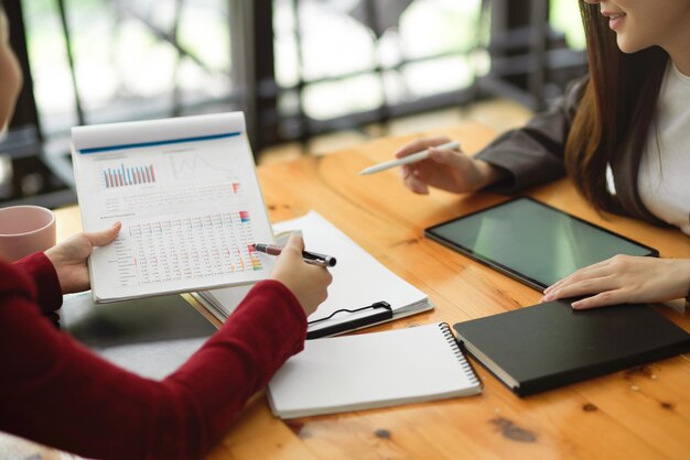 Duas das colegas de mulher de negócios olhando para a planilha de dados da empresa juntas no escritório.