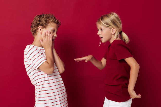 Duas emoções de crianças alegres ficam lado a lado em roupas cotidianas isoladas de fundo