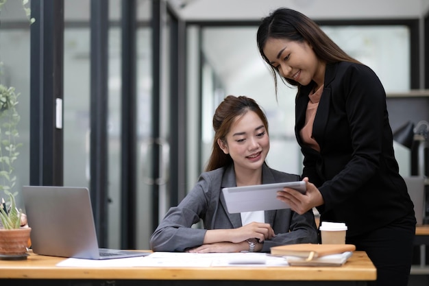 Duas empresárias asiáticas trabalham juntas para fazer o trabalho no escritório