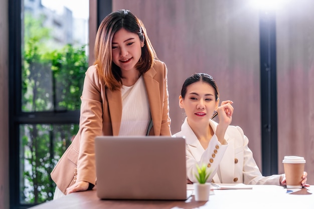 Duas empresárias asiáticas trabalhando com a empresa parceira por meio de um laptop de tecnologia