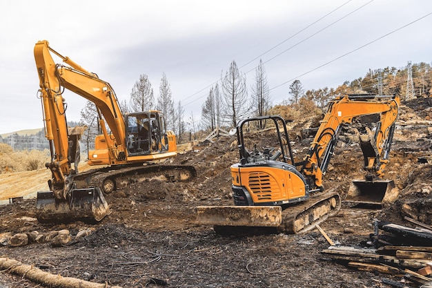 Duas escavadeiras limpam uma colina de terra para construção