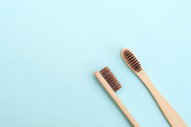 Duas escovas de dentes de bambu em um fundo azul. Lugar para texto. Fundo