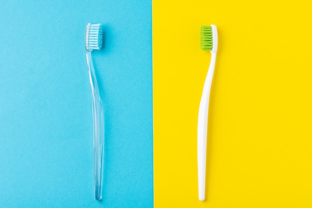 Duas escovas de dentes de plástico em azul pastel e amarelo, estilo liso leigo