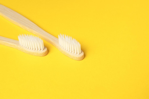 Foto duas escovas de dentes ecológicas de bambu de madeira em fundo amarelo cuidados dentários e zero desperdício