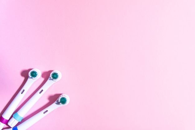 Duas escovas de dentes elétricas em um fundo rosa claro suave.