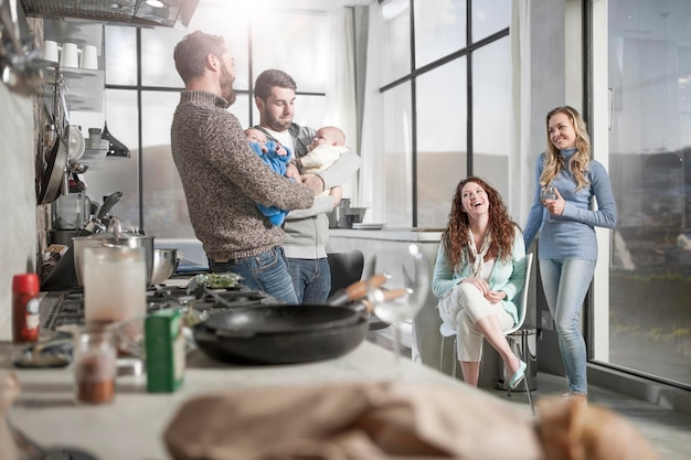 Duas esposas assistindo maridos segurando seus bebês na cozinha