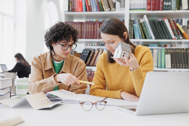 Duas estudantes de arquitetura na biblioteca discutem o projeto amigas e colegas designers