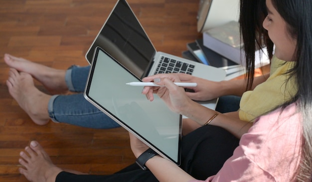 Duas estudantes universitárias usam um tablet e um laptop para estudar on-line em casa