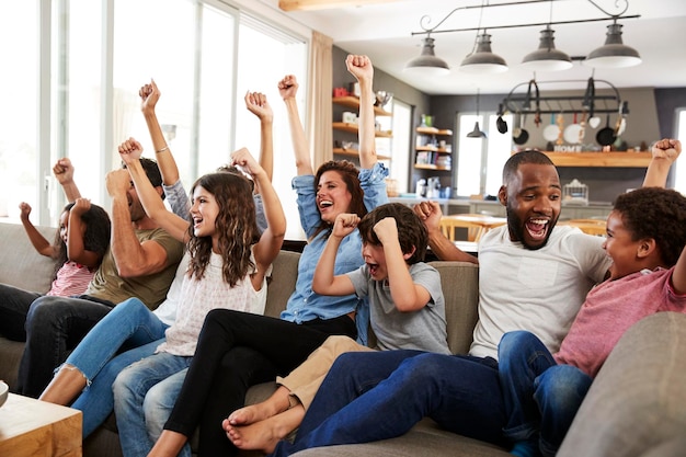 Duas famílias assistindo esportes na televisão e torcendo