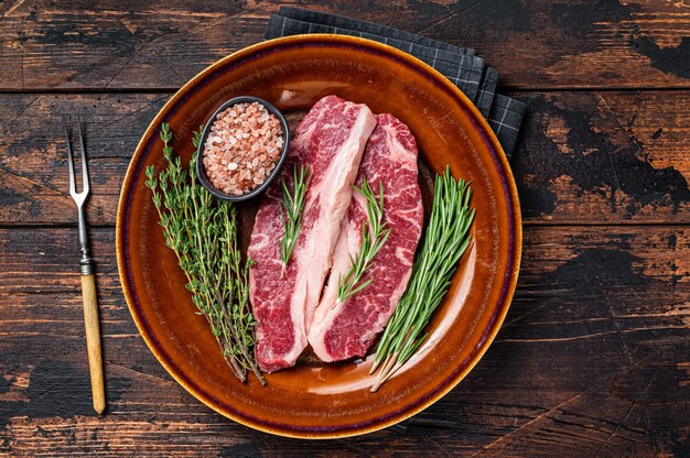 Duas fatias de bifes Raw Striploin ou bifes de Nova York, carne bovina. Fundo de madeira escuro. Vista do topo.