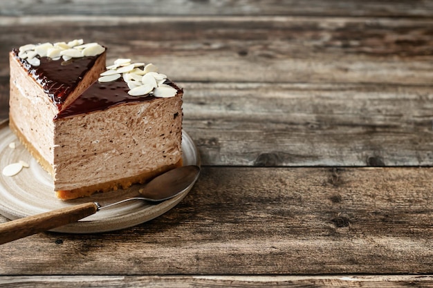 Duas fatias de cheesecake de chocolate com pétalas de amêndoa no fundo de madeira Copiar espaço