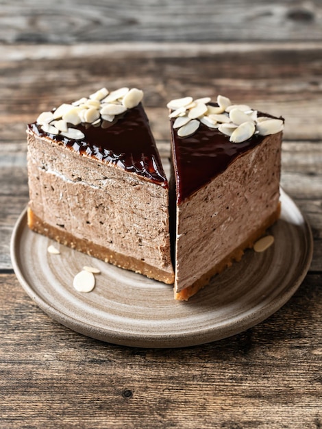 Duas fatias de cheesecake de chocolate vitrificadas com pétalas de amêndoa no topo de fundo de madeira