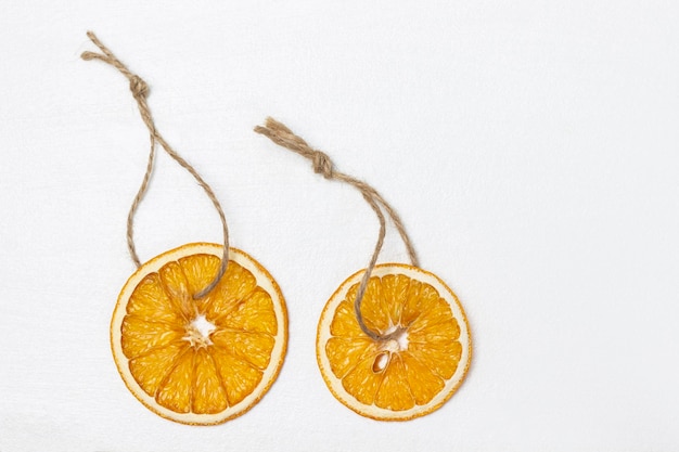 Duas fatias de laranja seca em uma decoração de cordas para a árvore de Natal
