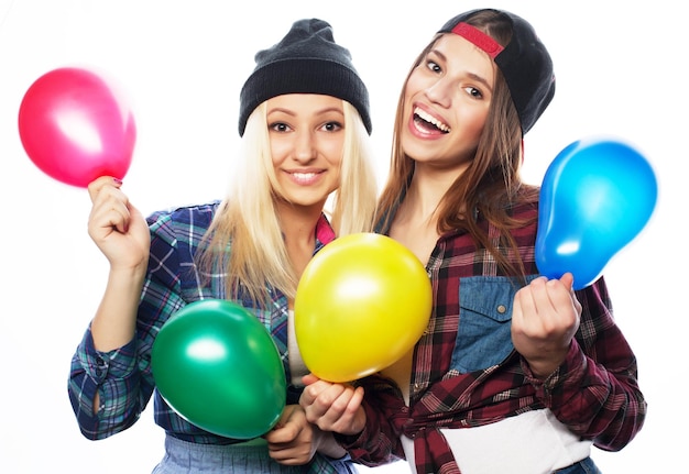 Duas felizes garotas hippie sorrindo e segurando balões coloridos sobre fundo branco