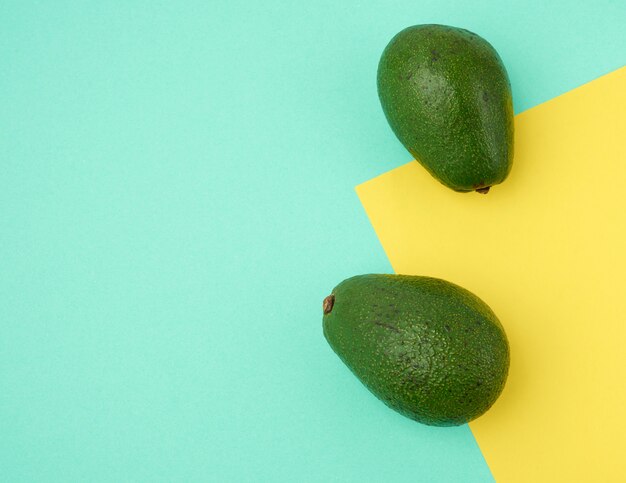 Duas frutas de abacate verdes sobre um fundo verde-amarelo, vista superior