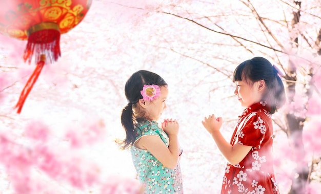 Duas garotas adoráveis vestindo cheongsam durante a temporada de ano novo chinês xA