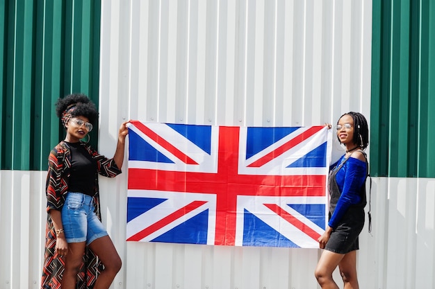 Duas garotas afro-americanas com bandeira da Grã-Bretanha nas mãos