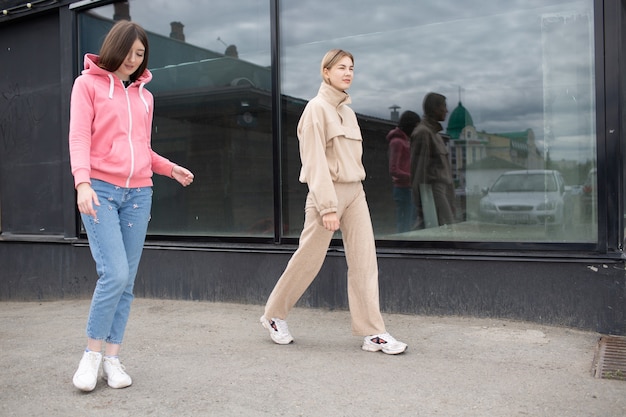 Duas garotas andando na rua da cidade. Jovem mulher ao ar livre.