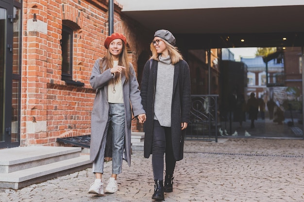 Duas garotas andando na rua juntas estão vestindo roupas de primavera ou outono e estão felizes