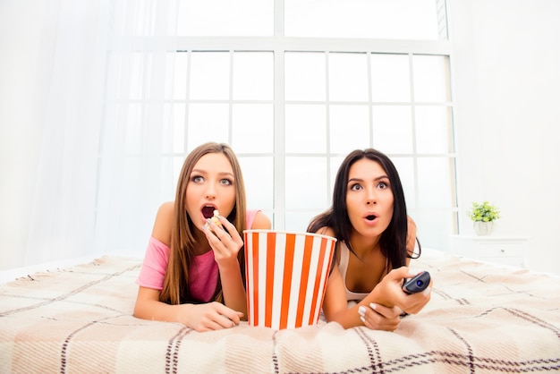 Duas garotas animadas assistindo filme e comendo pipoca