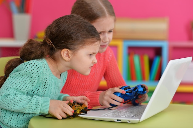 Foto duas garotas animadas jogando no laptop em casa