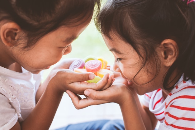 Duas garotas asiáticas criança segurando doces doces em suas mãos