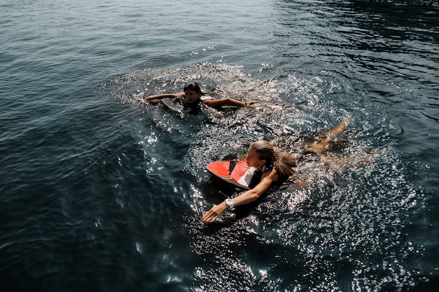 Duas garotas atraentes nadando no wakeboard no lago