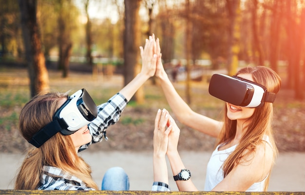 Duas garotas bonitas desfrutar de óculos de realidade virtual ao ar livre