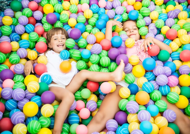 Duas garotas brincando na piscina com bolas de plástico