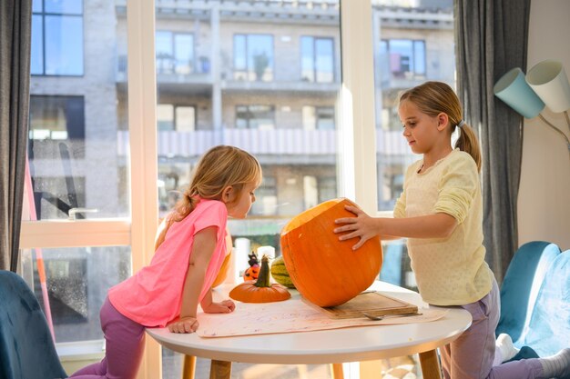 Duas garotas cortando abóbora de Halloween