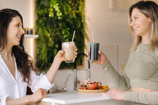 Duas garotas de aparência esportiva com coquetéis nas mãos discutem alimentação e dieta saudáveis