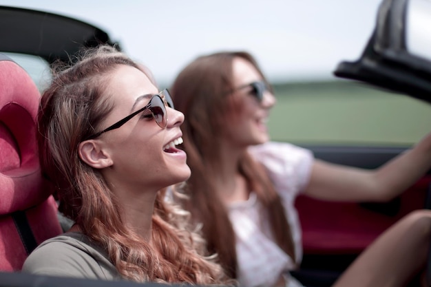 Duas garotas elegantes viajam em um carro conversível