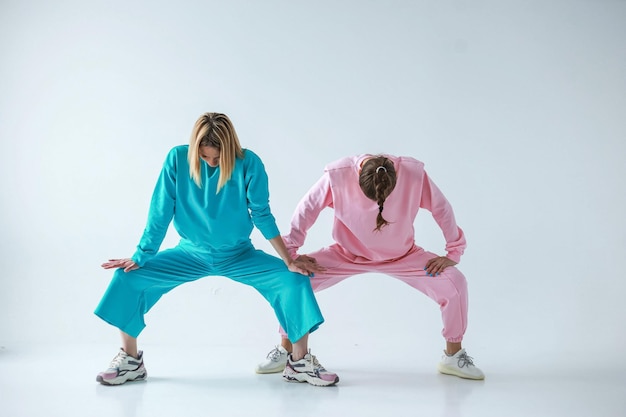 Duas garotas em roupas esportivas elegantes e aconchegantes contra um fundo brilhante, estúdio fotografando para uma revista, detalhes de tecidos e flores