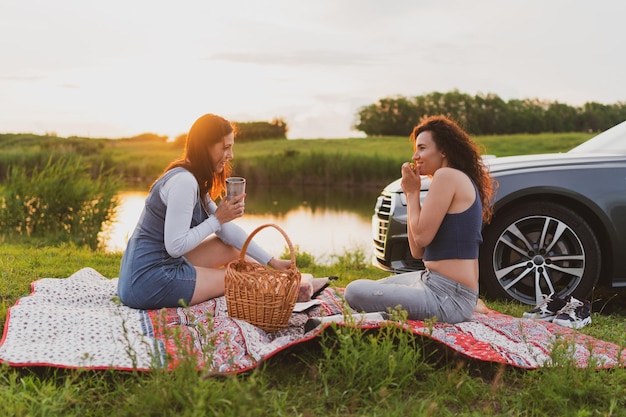 Duas garotas estão viajando nas estradas de carro e paradas para um piquenique na estrada Conceito de férias