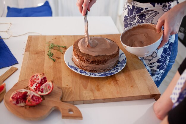 Duas garotas fazendo um bolo na cozinha. Mãos femininas, causando o creme de chocolate