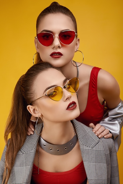 Duas garotas gêmeas hipster glamour elegante em moda top vermelho, calções pretos