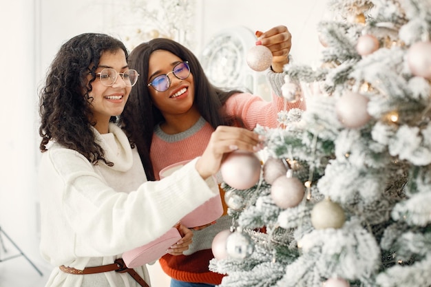 Duas garotas indianas em óculos decorando a árvore de Natal