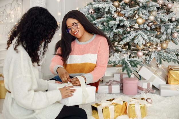 Duas garotas indianas em óculos sentados perto da árvore de Natal